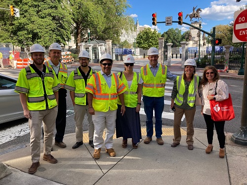 Group of seven people in construction vests and hard hats with A H A Staff member.